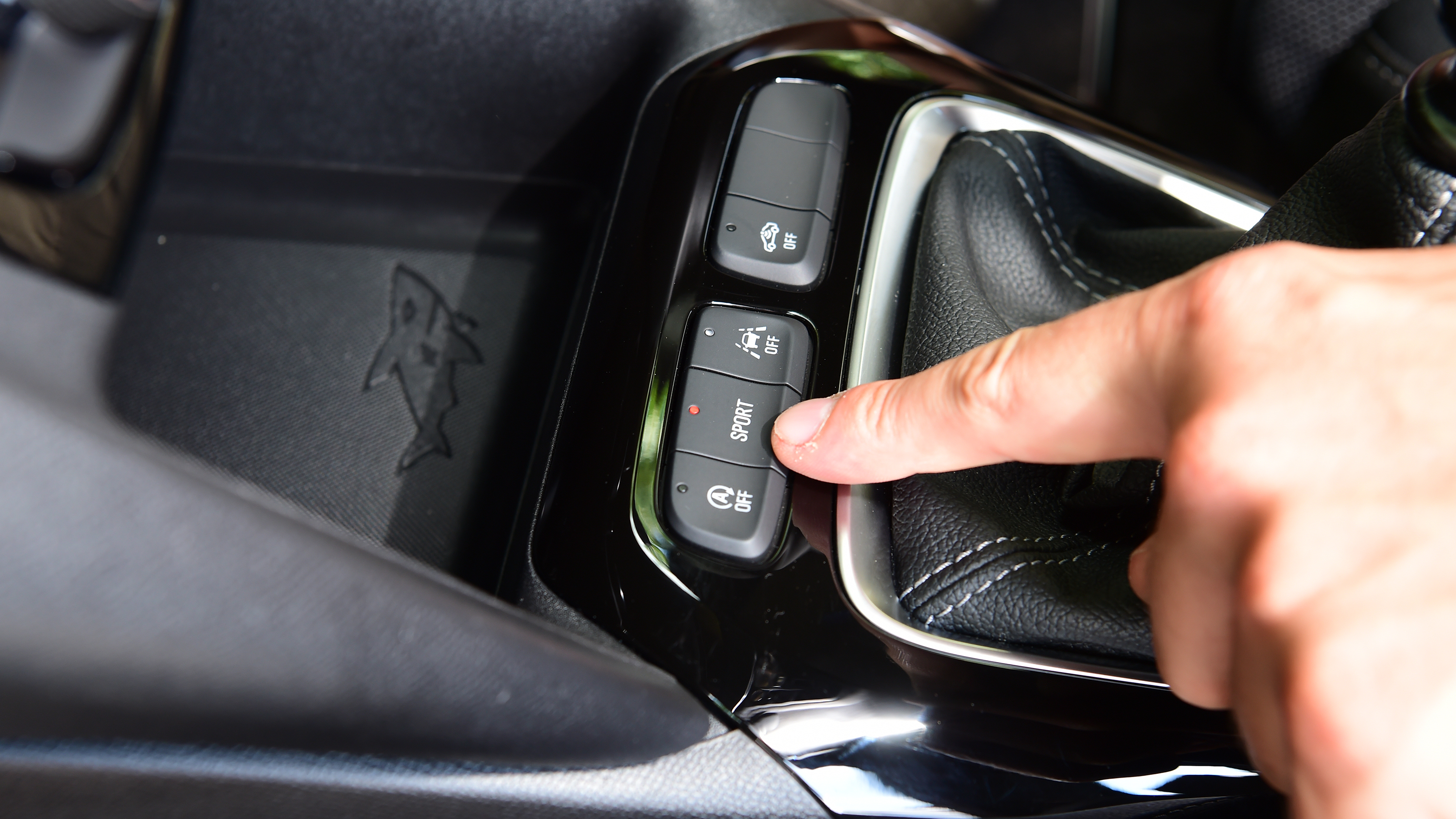 Auto Express senior news reporter Alastair Crooks pointing at the sport button in the Vauxhall Corsa GS
