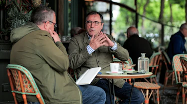 Dacia CEO Denis Le Vot and John McIlroy sitting outside a French cafe