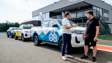 Hydrogen fuel-cell powered Toyota Hilux with Auto Express consumer reporter Tom Jervis talking to a Toyota engineer in front of some pick-up trucks