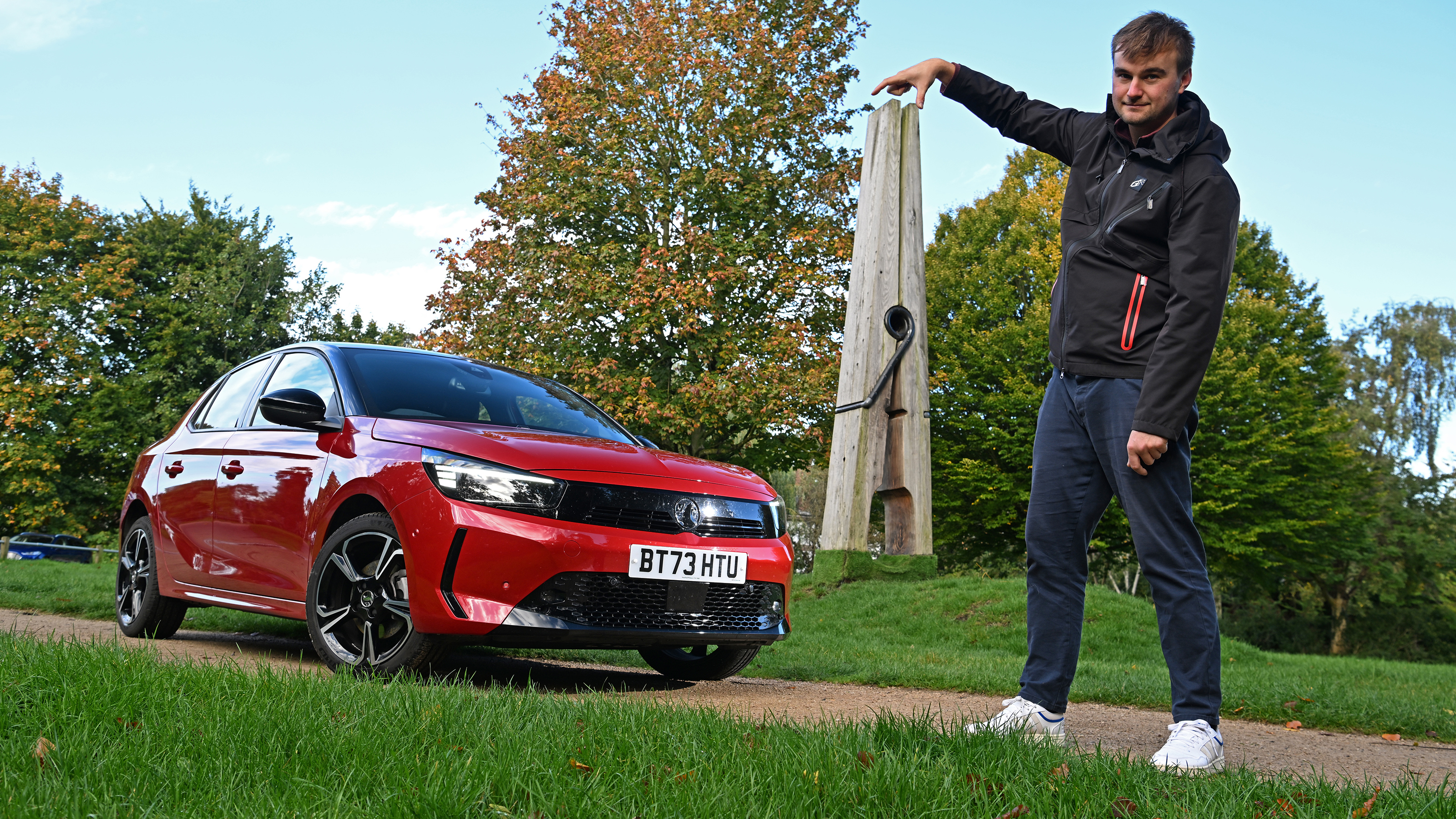 Auto Express senior news reporter Alastair Crooks holding a giant clothes peg while standing next to the Vauxhall Corsa GS