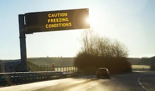 Motorway gantry sign displaying 'caution freezing conditions' message