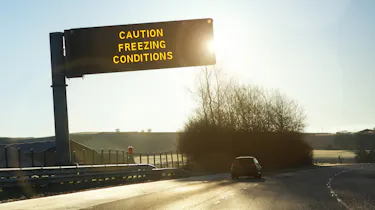 Motorway gantry sign displaying 'caution freezing conditions' message