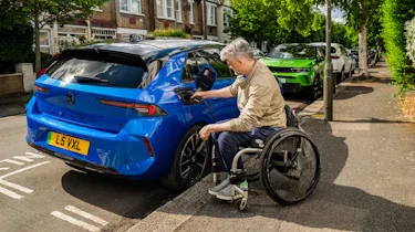 Wheelchair user plugging a charging cable into a Vauxhall Astra Electric