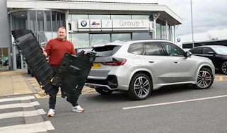 Auto Express news reporter Ellis Hyde holding two BMW iX1 undertrays