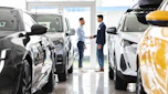 Car salesperson shaking hands with a customer in a showroom