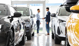 Car salesperson shaking hands with a customer in a showroom