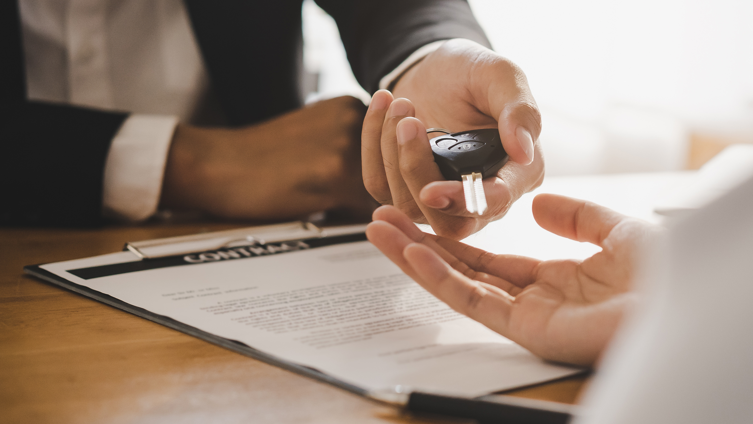 Salesperson handing car key to customer