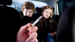 Person smoking in car in front of children