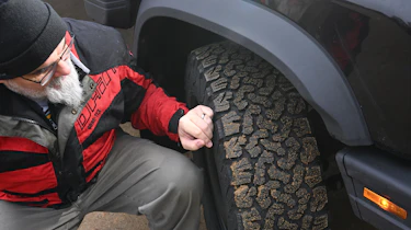 Auto Express senior test editor Dean Gibson inspecting the Ineos Grenadier's tyre