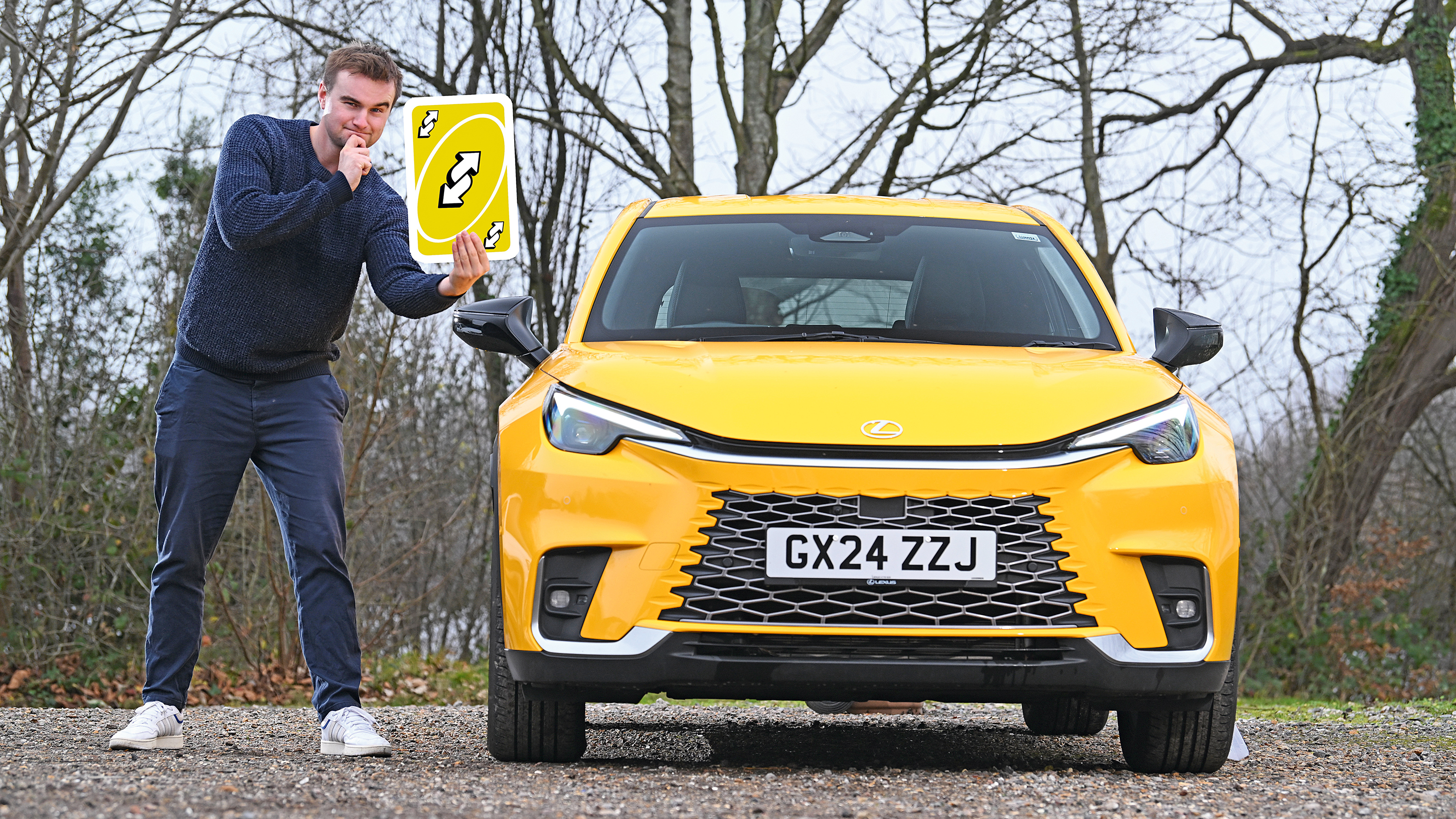 Auto Express senior news reporter Alastair Crooks standing next to the Lexus LBX while holding a giant Uno playing card