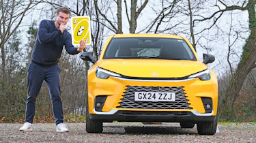 Auto Express senior news reporter Alastair Crooks standing next to the Lexus LBX while holding a giant Uno playing card