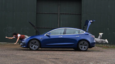 Auto Express senior staff writer Jordan Katsianis leaning out of the Tesla's front and rear storage areas