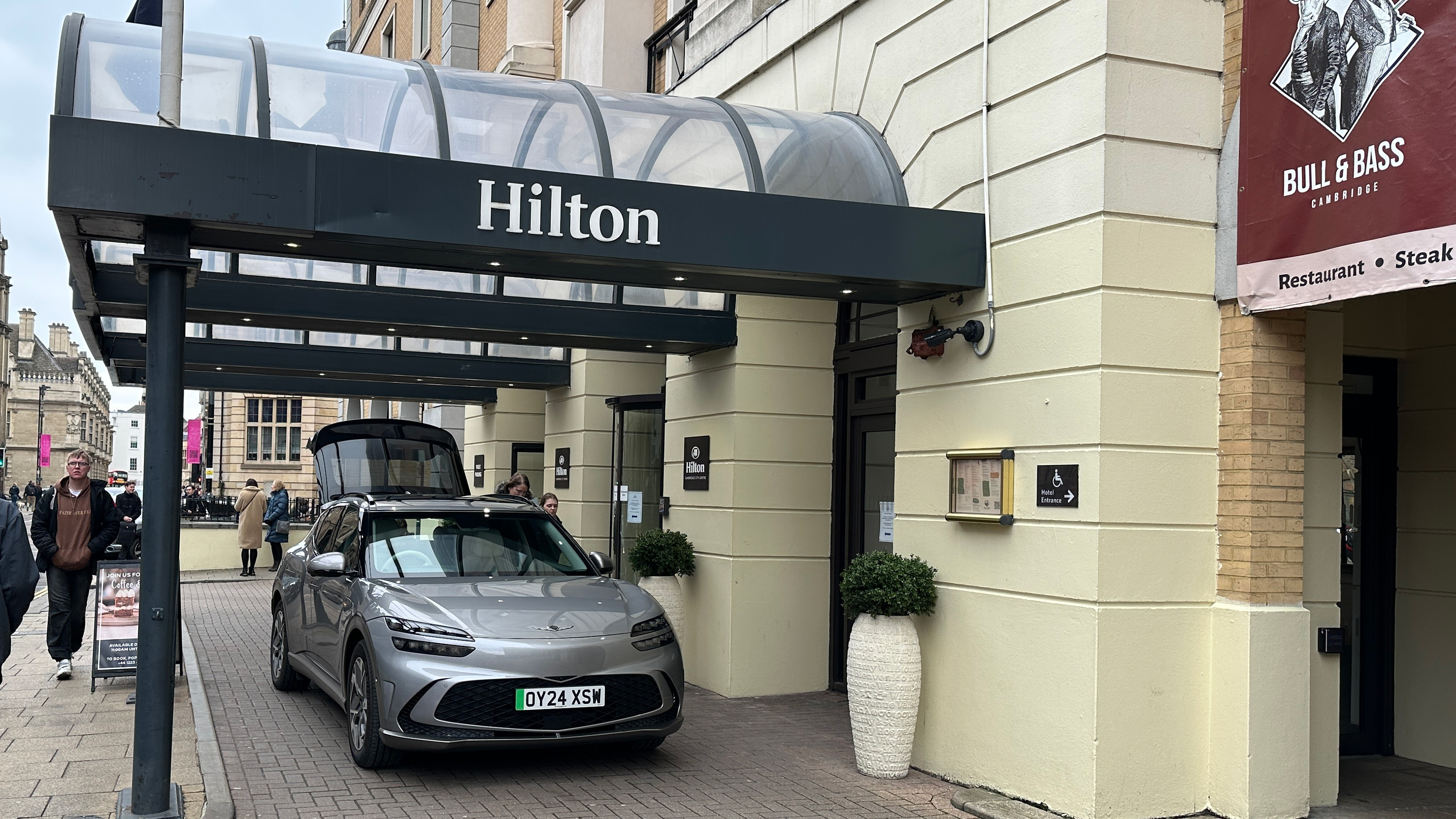 Genesis GV60 parked underneath a Hilton hotel entrance canopy
