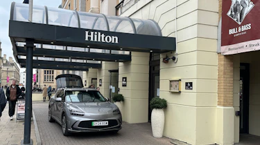Genesis GV60 parked underneath a Hilton hotel entrance canopy