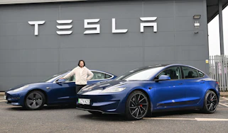 Auto Express senior staff writer Jordan Katsianis standing between two Tesla Model 3s