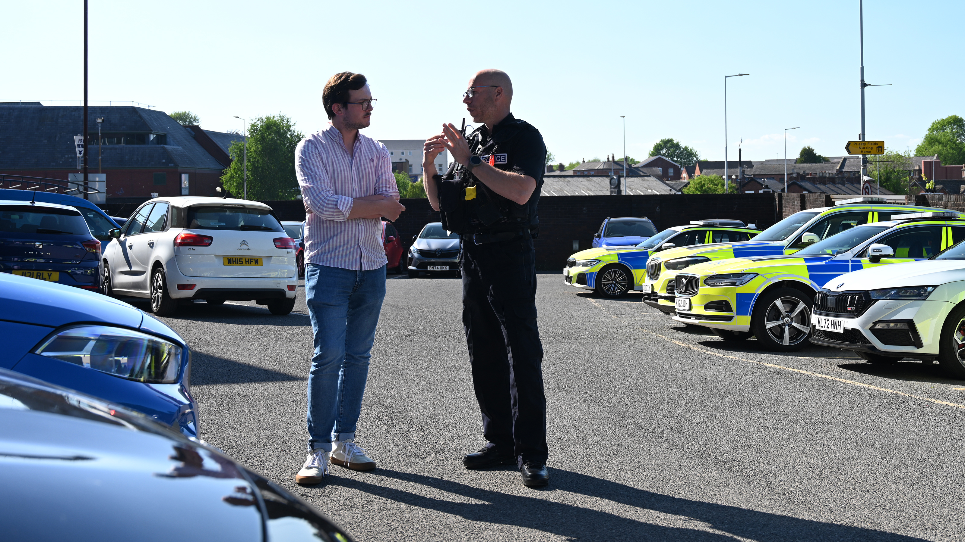 Auto Express consumer reporter Tom Jervis talking to PC Mark Jones in front of a fleet of police cars