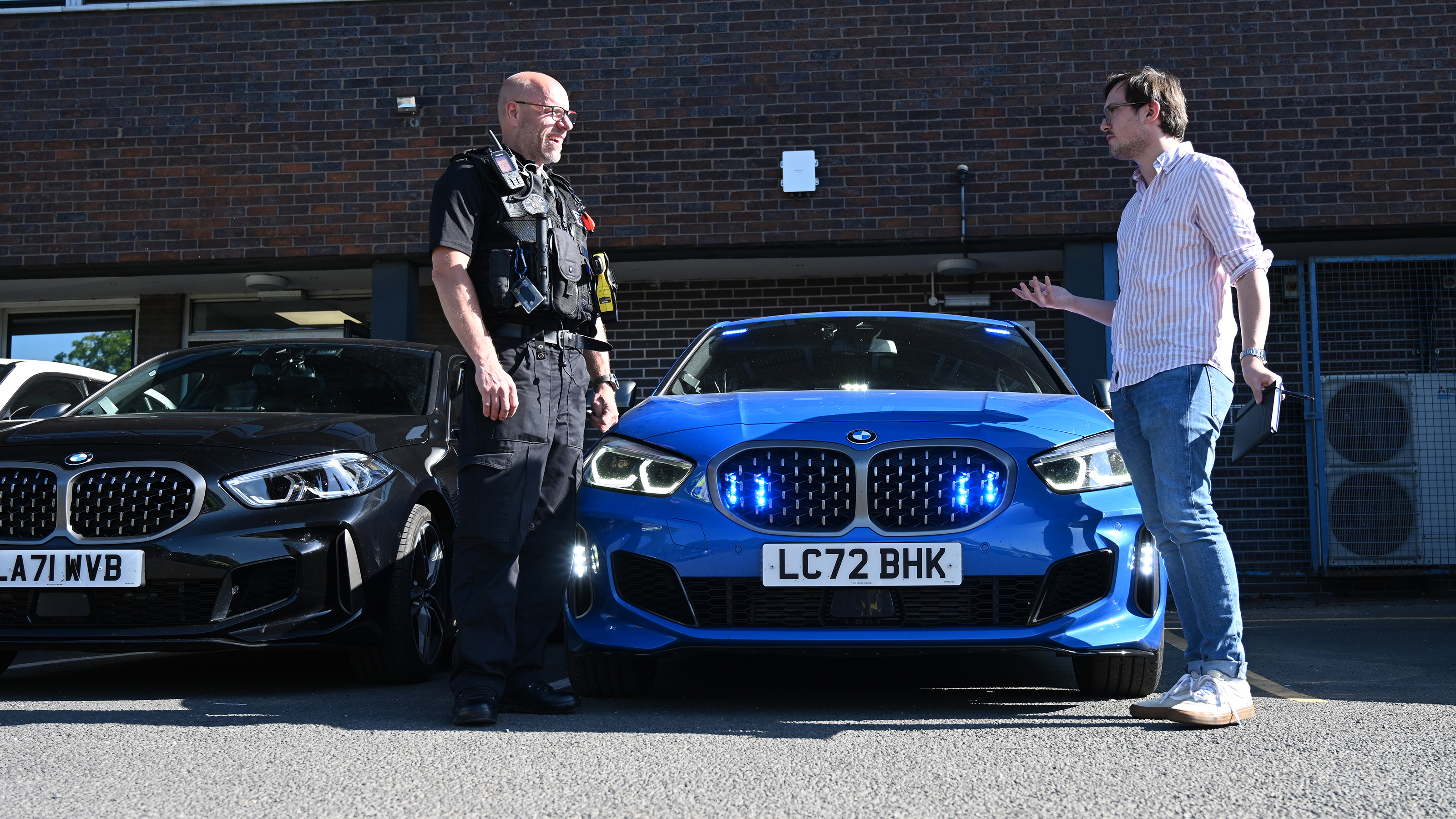 Auto Express consumer reporter Tom Jervis talking to PC Mark Jones in front of a police BMW 1 Series