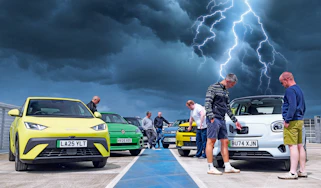 Auto Express team standing with a selection of EVs underneath a lightning storm