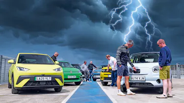 Auto Express team standing with a selection of EVs underneath a lightning storm