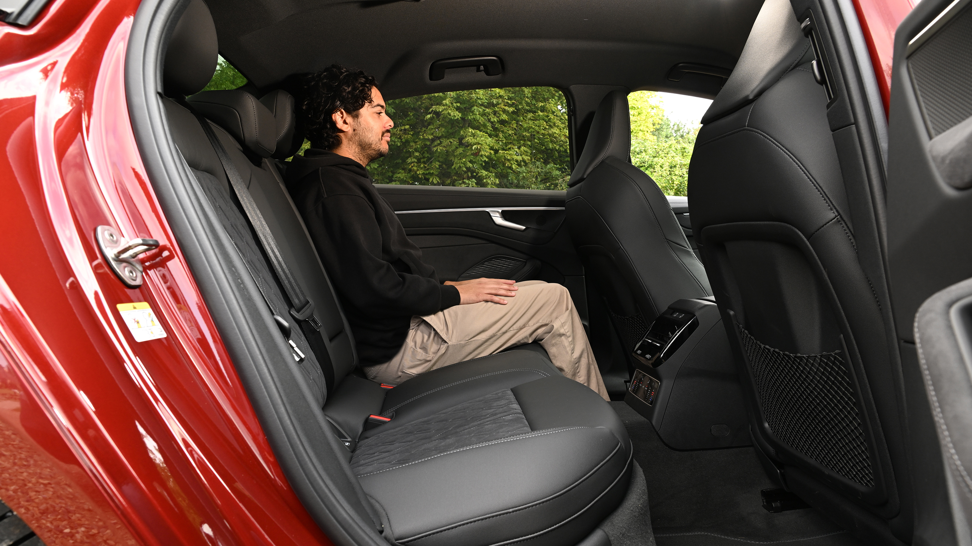 Auto Express senior news editor Jordan Katsianis sitting in the Audi A6 e-Hybrid's back seat