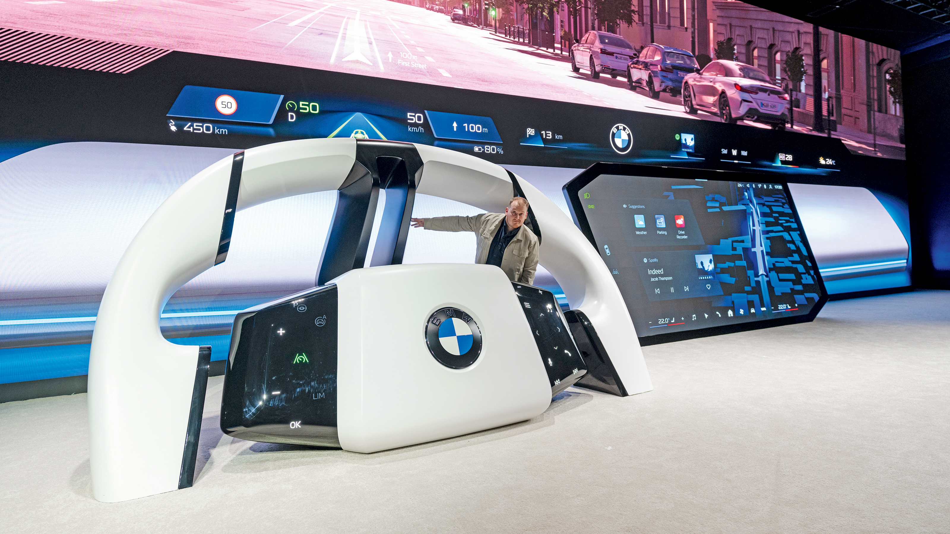 Auto Express news reporter Ellis Hyde sitting on a giant BMW steering wheel