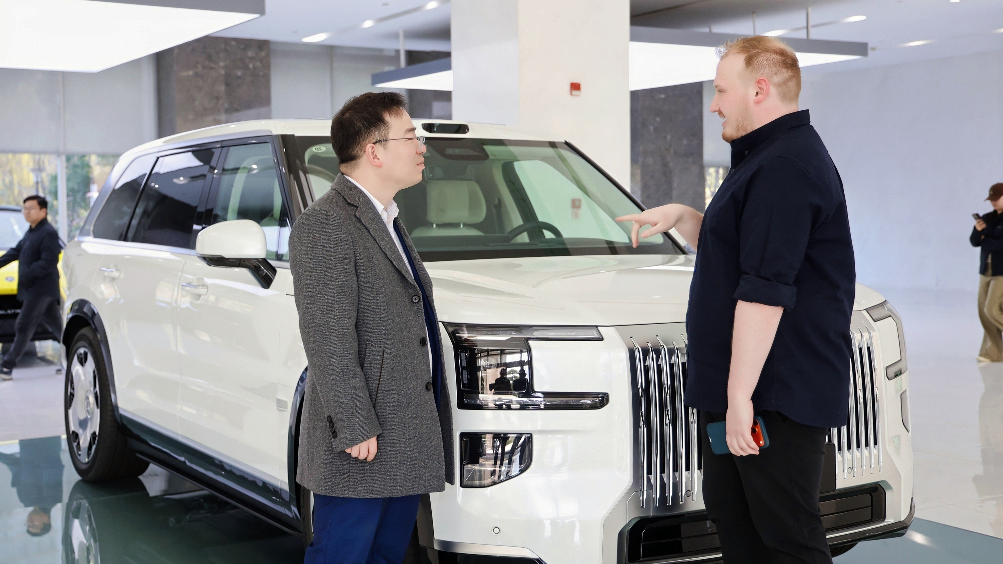 Auto Express news reporter Ellis Hyde and Geely UK managing director Mike Yang standing in front of a Zeekr 9X