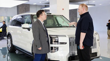Auto Express news reporter Ellis Hyde and Geely UK managing director Mike Yang standing in front of a Zeekr 9X