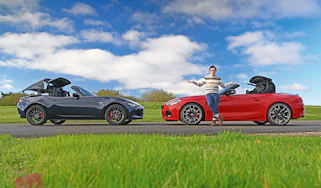 Auto Express consumer reporter Tom Jervis standing in front of a Mazda MX-5 and BMW Z4