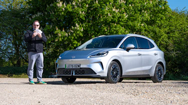 Auto Express web producer Pete Baiden standing next to the MG4 Urban while holding a wad of cash