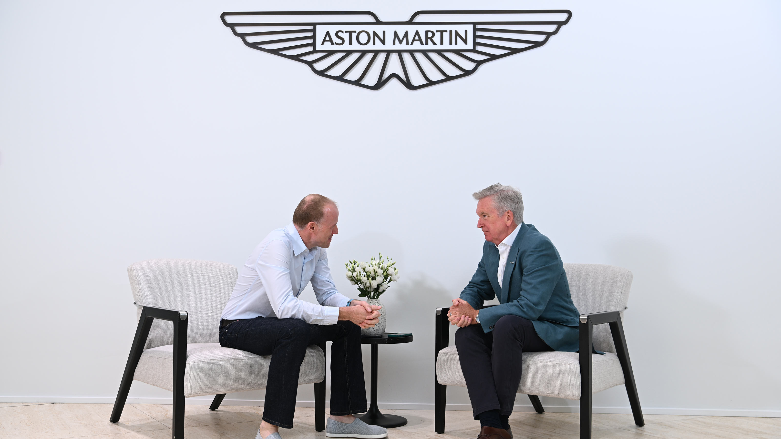 Aston CEO Adrian Hallmark talking to Phil McNamara under logo