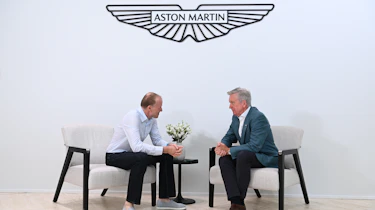 Aston CEO Adrian Hallmark talking to Phil McNamara under logo