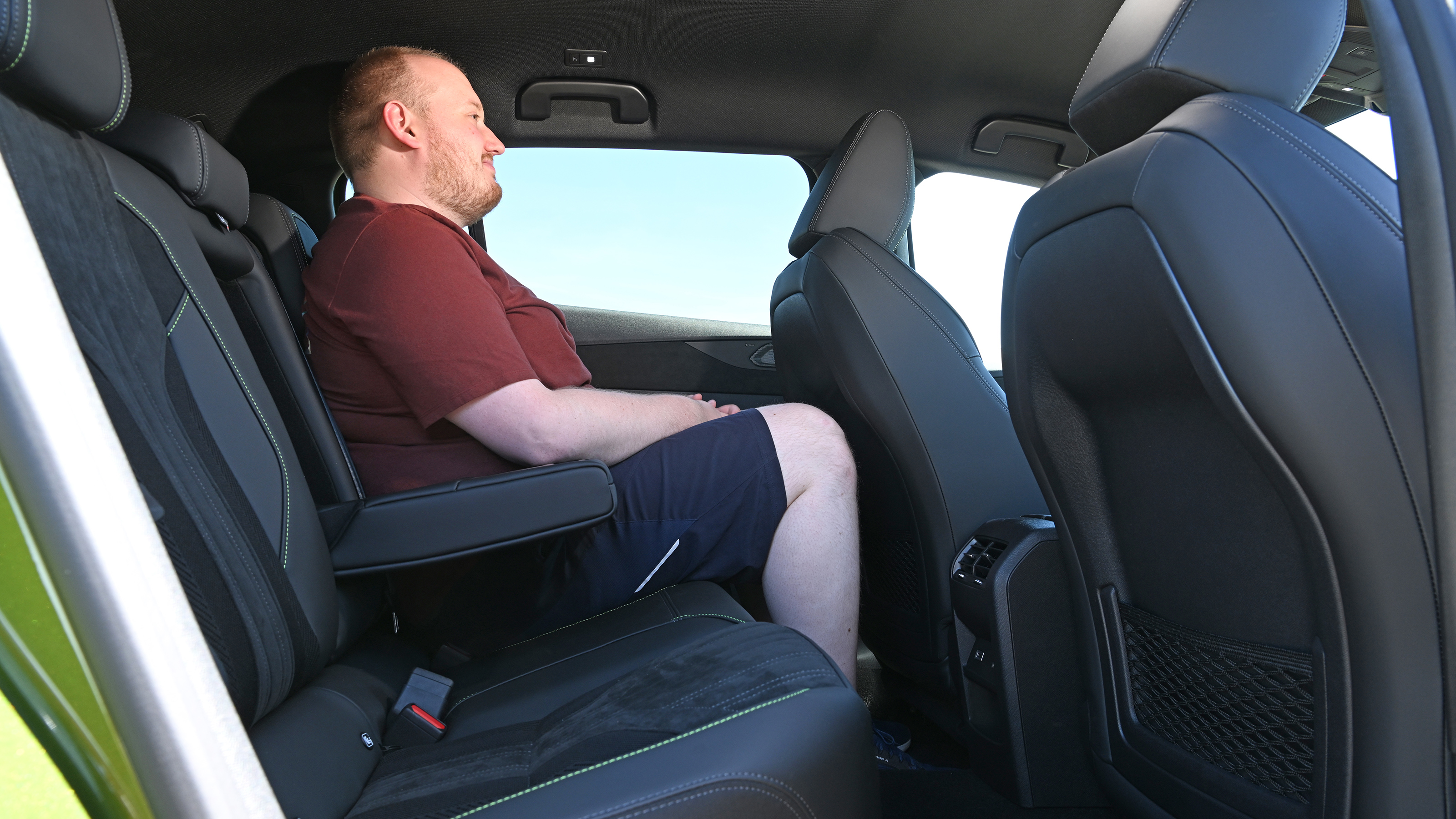 Auto Express news reporter Ellis Hyde sitting in the Peugeot E-408's rear seat