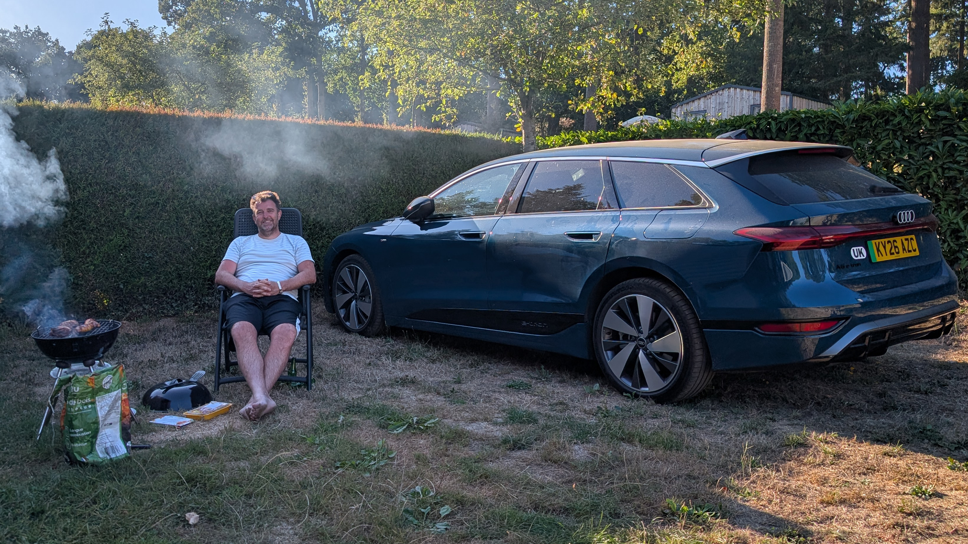 Auto Express head of digital content Steve Walker sitting between the Audi A6 Avant e-tron and a barbecue