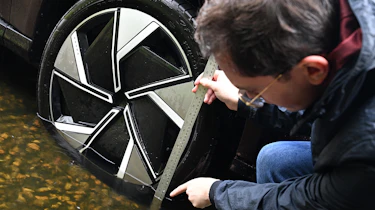 Auto Express consumer reporter Tom Jervis measuring water depth on a Volvo EX90 wheel
