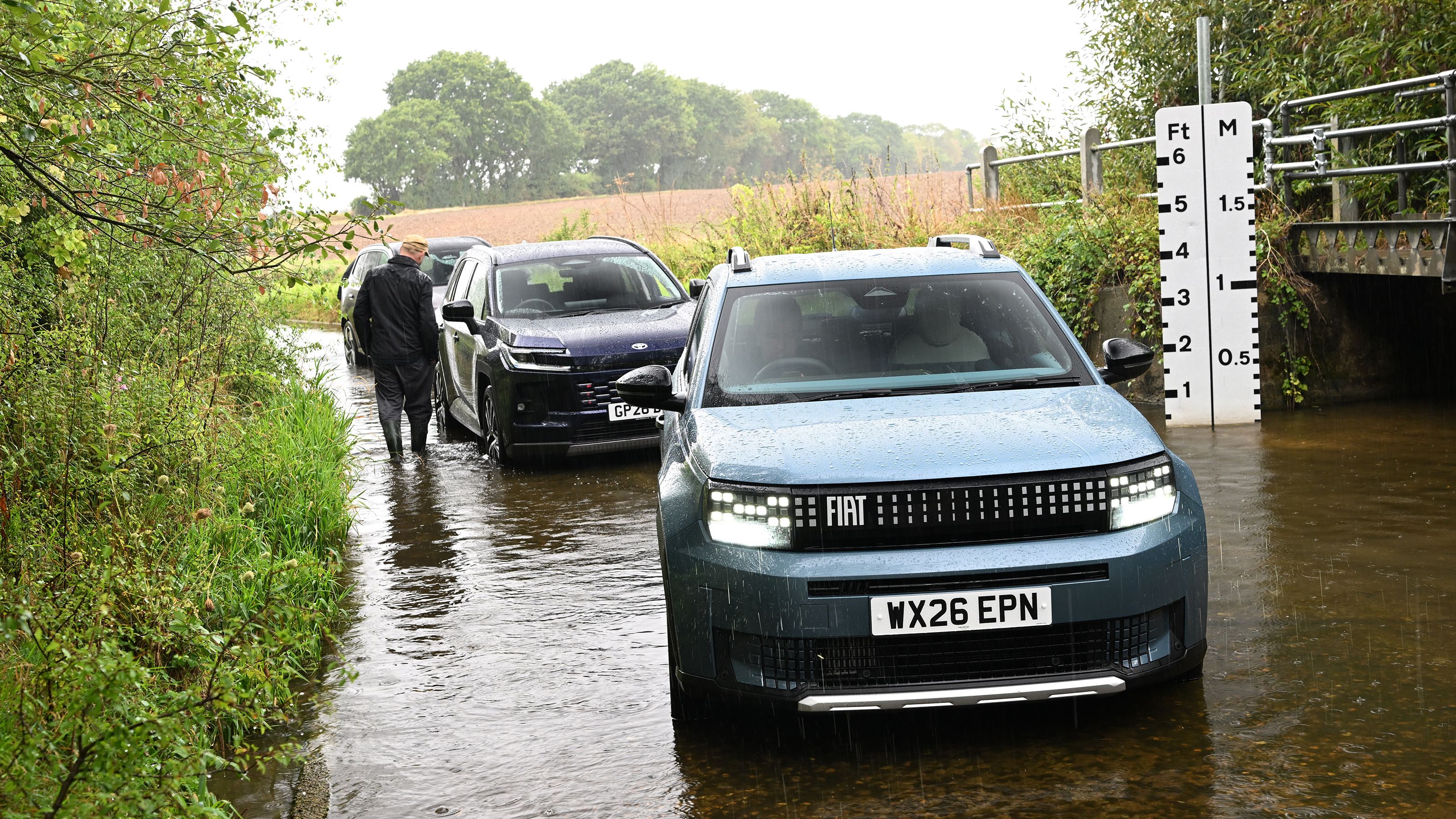Three cars driving through a ford