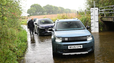Three cars driving through a ford