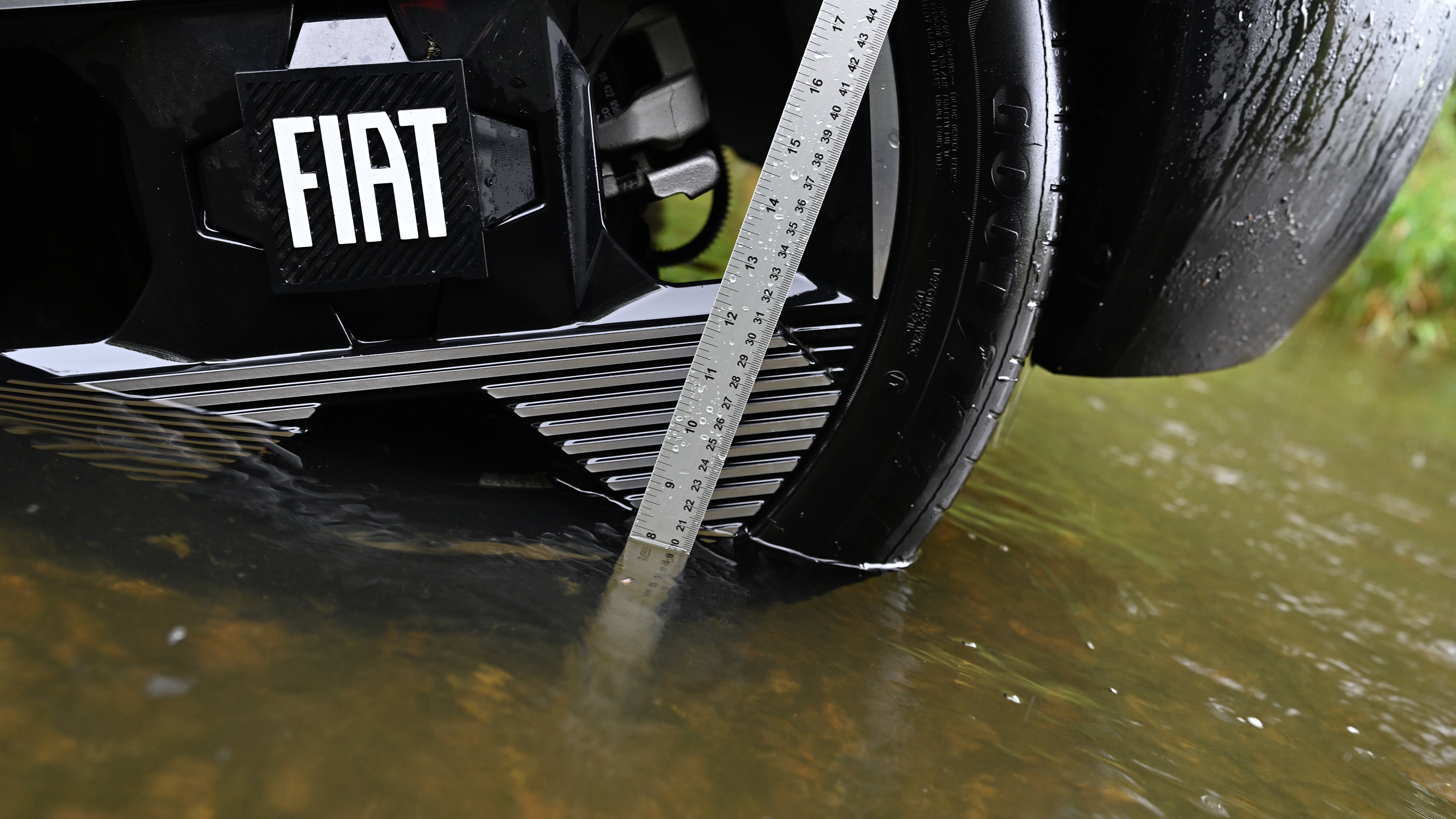 Metal ruler measuring water depth on a Fiat Grande Panda wheel